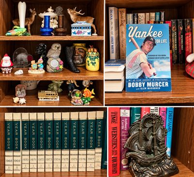 Sale Photo Thumbnail #10: Wooden shelves displaying an assortment of collectibles, including deer figurines, colored glass vases, vintage yearbooks, a brass sailing ship bookend, and paperback books.