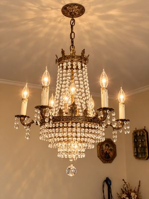 Sale Photo Thumbnail #28: Ornate vintage brass chandelier featuring multiple candelabra lights, draped crystal bead strands, and tiered faceted prisms.