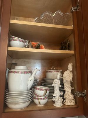 Sale Photo Thumbnail #47: Vintage porcelain tea set with floral bands and gilt accents displayed in a cabinet alongside white Guan Yin figurines and cut crystal.