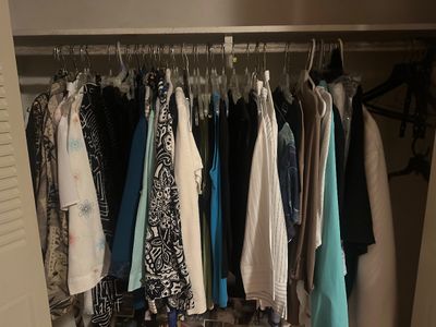 Sale Photo Thumbnail #43: Closet filled with assorted women's tops, blouses, and jackets hanging on wire and plastic hangers.