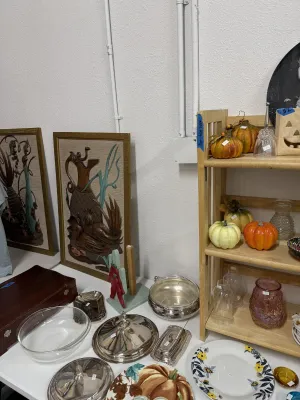 Sale Photo Thumbnail #11: Collection of home decor items featuring mid-century framed relief wall art, silver-plated serving dishes, fall-themed ceramic pumpkins and plates, and various glassware.