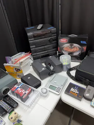 Sale Photo Thumbnail #28: A collection of electronics and household items including a vintage Sony stereo stack system with speakers, a Parini electric pizza cooker in box, cassette tapes, and small digital devices.