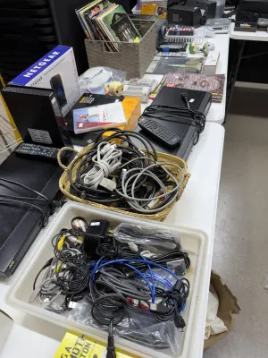 Sale Photo Thumbnail #31: Assorted home electronics including a Netgear router, a JVC video player with remote, and containers filled with various A/V and power cables.