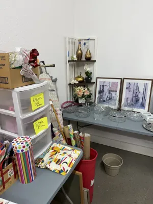Sale Photo Thumbnail #24: Collection of crafting supplies, gift wrap, plastic storage drawers, and clear glassware alongside framed architectural wall art.