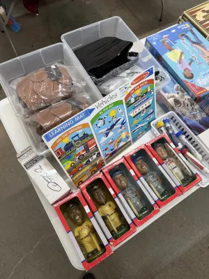 Sale Photo Thumbnail #16: Collection of assorted items including boxed hand-painted baseball player bobbleheads, leather handbags, children's learning games, and boxed play sets.