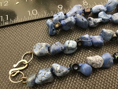 Sale Photo Thumbnail #56: A beaded necklace featuring blue stone nuggets/chunks interspersed with small dark accent beads. Features an S-hook clasp stamped '925' for sterling silver. Measures approximately 20-22 inches in total length. In good condition with natural inclusions and