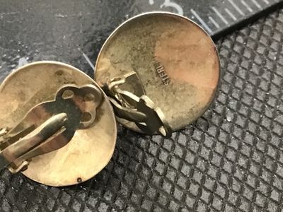 Sale Photo Thumbnail #107: Pair of vintage round clip-on earrings featuring polished black cabochons (likely onyx) bezel-set in sterling silver. Marked STERLING on the reverse. Show minor tarnish consistent with age. Each earring measures approximately 0.8 inches in diameter.