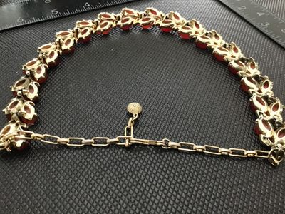 Sale Photo Thumbnail #101: Vintage gold-tone choker necklace featuring leaf-motif settings accented with alternating red and coral-tone navette/marquise lucite or glass cabochons. Includes an adjustable extension chain with a hook clasp and textured metal ball dangle. In good vinta