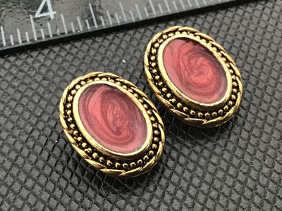 Sale Photo Thumbnail #6: Pair of vintage gold-tone oval clip-on earrings featuring reddish-pink marbled swirl centers with rope twist detail borders. Measurements shown against ruler for scale. Good vintage condition with light finish wear consistent with age.