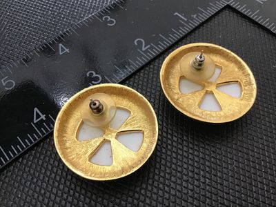 Sale Photo Thumbnail #138: Pair of vintage round button-style pierced earrings featuring a smooth white enamel center surrounded by a textured gold-tone metal border. Equipped with post backs and plastic disc clutch backings. Each earring measures approximately 1 inch in diameter. 