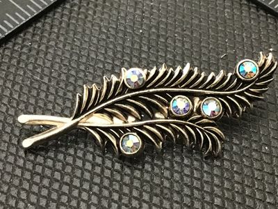 Sale Photo Thumbnail #113: A vintage silver-tone brooch designed in the shape of stylized leaves or feathers, accented with bezel-set iridescent aurora borealis rhinestones. Features a standard pin back with rollover safety clasp. Good pre-owned condition with light surface wear.