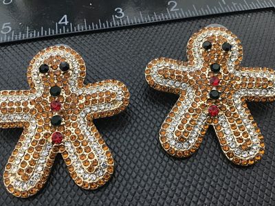 Sale Photo Thumbnail #39: Pair of festive holiday pierced post earrings shaped like gingerbread men, fully pave-set with amber, clear, red, and dark green/black rhinestones on a gold-tone metal backing. Each earring measures approximately 2 inches tall by 1.75 inches wide. Excelle
