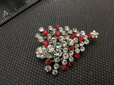 Sale Photo Thumbnail #119: Festive Christmas tree brooch features multi-colored clear, red, green, and aurora borealis (AB) rhinestones set in silver-tone metal. Measures approximately 2 inches in length. Features a rollover safety clasp on the back. Good pre-owned condition with a
