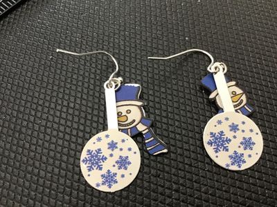 Sale Photo Thumbnail #184: Pair of festive winter drop/dangle earrings featuring snowmen wearing blue top hats and scarves alongside round snowflake charm pendants. Silver-tone French hook wire backs. Good pre-owned condition.