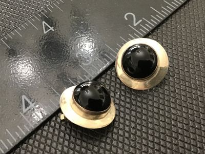 Sale Photo Thumbnail #106: Pair of vintage round clip-on earrings featuring polished black cabochons (likely onyx) bezel-set in sterling silver. Marked STERLING on the reverse. Show minor tarnish consistent with age. Each earring measures approximately 0.8 inches in diameter.