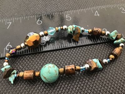 Sale Photo Thumbnail #54: A stretch beaded bracelet featuring faux or composite turquoise stones, tiger's eye-style chips, metallic spacers, and faceted iridescent glass or crystal beads. Measures approximately 7 inches in circumference. Good condition with light wear.