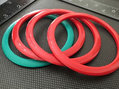 Sale Photo Thumbnail #157: Set of four lightweight plastic bangle bracelets, including three red and one green. Slim circular design. Measure approximately 2.5 to 3 inches in inner diameter. Good vintage condition with light surface wear.