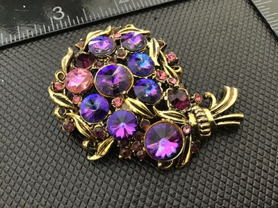 Sale Photo Thumbnail #41: Vintage gold-tone floral bouquet brooch set with vibrant purple, lavender, and pink rhinestones. Signed Hollycraft on the reverse. Features a rollover safety clasp. Measures approximately 2 inches in size. Pre-owned condition with light surface wear consi