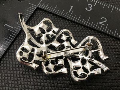 Sale Photo Thumbnail #109: A vintage mid-century silver-tone costume jewelry brooch featuring a stylized leaf or ribbon spray motif set with colorful aurora borealis rhinestones in pink, blue, and iridescent tones. Standard pin back mechanism with safety clasp. Measures approximate