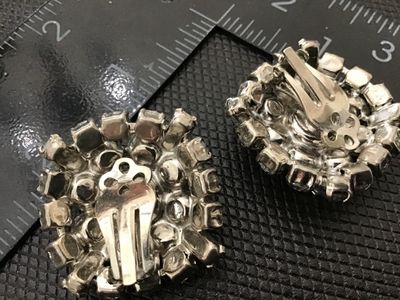Sale Photo Thumbnail #92: Pair of vintage round cluster clip-on earrings featuring bright clear rhinestones in silver-tone prong settings. Each earring measures approximately 1 inch in diameter. Clip-on backs are functional. Good vintage condition with clear stones and minor age-a