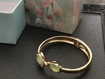Sale Photo Thumbnail #53: A Monet gold-tone hinged cuff/bangle bracelet featuring two sea turtles with light green translucent cabochon shells and clear rhinestone accents around the larger turtle. Includes original Monet gift box. Features a spring hinge closure. Marked MONET on 
