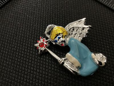 Sale Photo Thumbnail #117: A vintage silver-tone metal brooch depicting a flying angel or fairy in a light blue dress with textured wings, blonde hair, and holding a wand topped with a star and a red rhinestone accent. Features colorful enamel painted details. Pin back clasp mechan