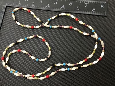 Sale Photo Thumbnail #98: Long beaded continuous necklace featuring white marquise/rice-shaped beads alternating with colorful accent beads in shades of turquoise blue, red, green, purple, black, and gold tone spacer beads. Measures approximately 30+ inches long in total strand le