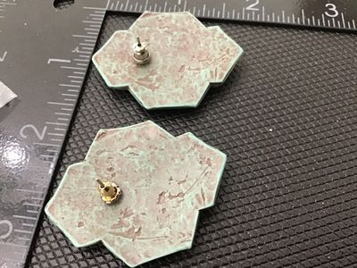 Sale Photo Thumbnail #90: Pair of vintage Southwestern style geometric pierced post earrings featuring a textured verdigris green finish over brown/copper metal accents. Geometric design with diamond and circle motifs. Measures approximately 1.5 inches. Good condition with light v