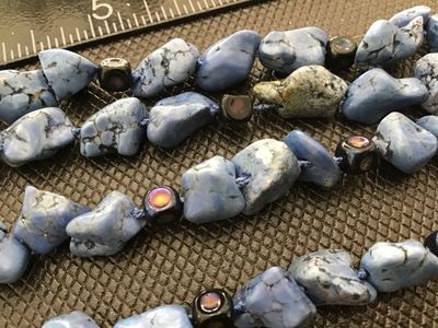 Sale Photo Thumbnail #58: A beaded necklace featuring blue stone nuggets/chunks interspersed with small dark accent beads. Features an S-hook clasp stamped '925' for sterling silver. Measures approximately 20-22 inches in total length. In good condition with natural inclusions and