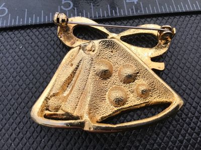 Sale Photo Thumbnail #38: A festive gold-tone Christmas brooch designed as double bells topped with a bow. The bells feature brushed texture accents and are set with colorful red, blue, green, and clear rhinestone accents. Measures approximately 1.5 inches wide. Includes a standar