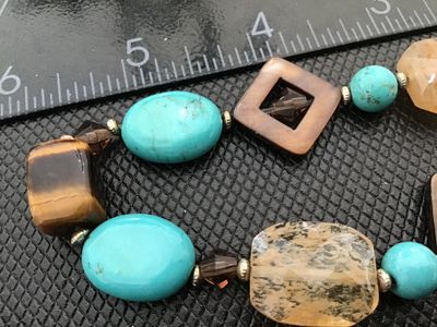 Sale Photo Thumbnail #22: A beaded costume jewelry set including a stretch bracelet and a pair of matching dangle/drop earrings. Features turquoise-colored composite beads, tiger's eye, jasper-like natural stones, and faceted glass accent beads. Earrings feature silver-tone fishho