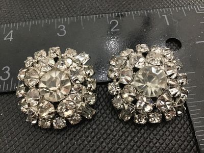 Sale Photo Thumbnail #94: Pair of vintage round cluster clip-on earrings featuring bright clear rhinestones in silver-tone prong settings. Each earring measures approximately 1 inch in diameter. Clip-on backs are functional. Good vintage condition with clear stones and minor age-a