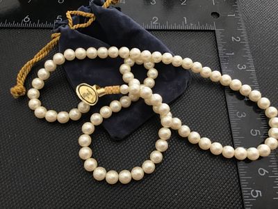 Sale Photo Thumbnail #177: Single-strand cream-colored faux pearl necklace featuring a gold-tone clasp and original gold tag marked 'MIKINI CULTURA' on one side and 'MADE IN JAPAN' on the reverse. Comes with a blue velvet drawstring pouch. Measures approximately 18-20 inches long w