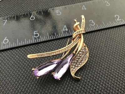 Sale Photo Thumbnail #8: Gold-tone metal floral spray brooch pin featuring two large pear/teardrop-cut light purple or amethyst-colored rhinestones and accented with clear pave-set rhinestones along the stem and leaf. Measures approximately 2.5 inches in length. Features a standa