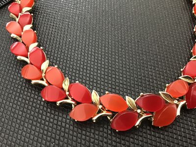 Sale Photo Thumbnail #100: Vintage gold-tone choker necklace featuring leaf-motif settings accented with alternating red and coral-tone navette/marquise lucite or glass cabochons. Includes an adjustable extension chain with a hook clasp and textured metal ball dangle. In good vinta