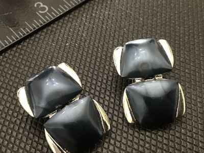 Sale Photo Thumbnail #123: Pair of vintage silver-tone clip-on earrings featuring dark blue-grey geometric resin or lucite cabochons set in two-tier articulated frames. Measure approximately 1 inch in length. Shows light vintage wear with clips in working condition.