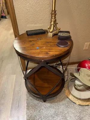 Sale Photo Thumbnail #9: Rustic round end table with a planked wooden top, lower tier shelf, and dark metal X-frame accents.