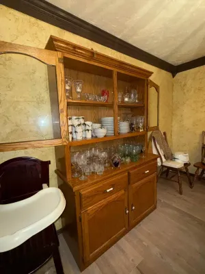 Sale Photo Thumbnail #11: Traditional oak china hutch filled with various glassware, stemware, and china dishes.
