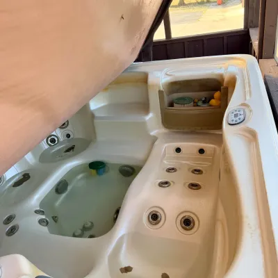 Sale Photo Thumbnail #7: Outdoor hot tub spa with an open cover, featuring multi-level seating, integrated massage jets, and digital control panel.