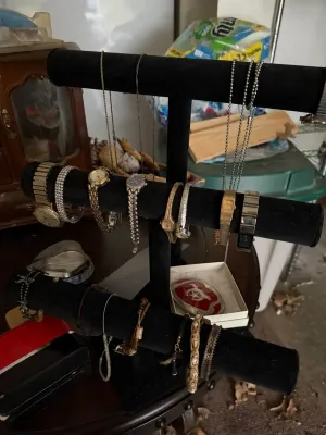 Sale Photo Thumbnail #19: Black velvet T-bar display stand holding an assortment of vintage women's wristwatches, beaded bracelets, and chain necklaces.
