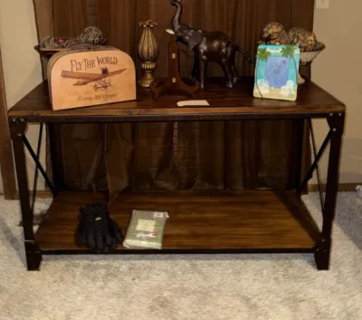 Sale Photo Thumbnail #13: Rustic industrial console table with dark wood shelves and a metal frame, displaying various decorative items including a hand-carved elephant figurine and vintage-style decor.