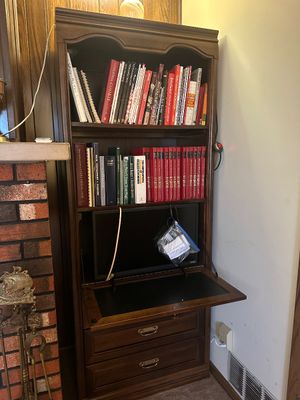 Sale Photo Thumbnail #37: Traditional dark wood secretary bookcase featuring open upper shelves filled with books, a pull-down desk compartment housing a small Vizio flat-screen monitor, and two lower storage drawers.