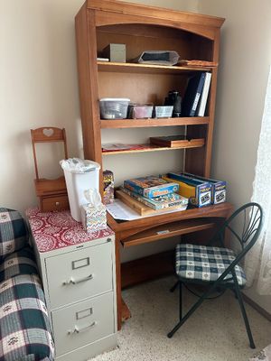 Sale Photo Thumbnail #23: Wooden student desk with attached hutch bookcase, filled with board games, office supplies, and paired with a green metal folding chair.