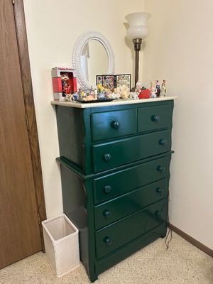 Sale Photo Thumbnail #16: Dark green painted chest-on-chest dresser topped with various collectibles, a white oval mirror, and a floor lamp.
