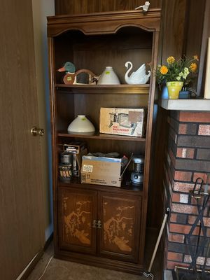 Sale Photo Thumbnail #32: Traditional dark wood bookcase cabinet featuring bottom doors with Asian-style tree motifs, filled with assorted home goods including glass lampshades and decorative figurines.