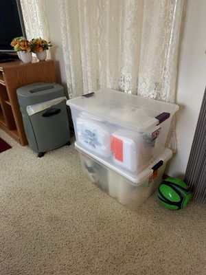 Sale Photo Thumbnail #27: Two stacked clear plastic storage totes filled with household items, paired with a green paper shredder on wheels and a green and black soccer ball.