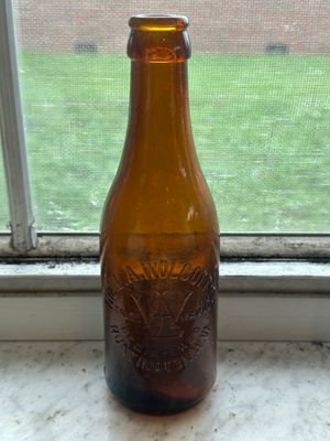 Sale Photo Thumbnail #62: Vintage amber glass bottle featuring embossed lettering for The L. A. Wolcott Co. from Huntington, West Virginia.