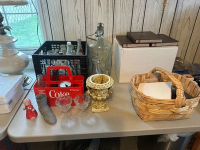 Sale Photo Thumbnail #42: Collection of vintage table items, including a red plastic Coca-Cola bottle carrier, glass milk and soda bottles in a crate, a woven basket, and decorative urn planters.