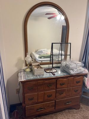 Sale Photo Thumbnail #2: Vintage traditional oak dresser featuring sculpted drawer fronts, brass bale handles, and a large arched wall-mounted mirror.