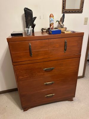 Sale Photo Thumbnail #14: Mid-century wooden tall chest of drawers with decorative brass hardware, holding various small household decor items on top.